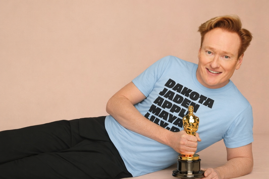 Comedian Conan O’Brien holding an Oscar statue while wearing the Nepo Babies List Unisex T-Shirt from the Tantrum Media Store Entertainment Collection, referencing Hollywood nepotism culture