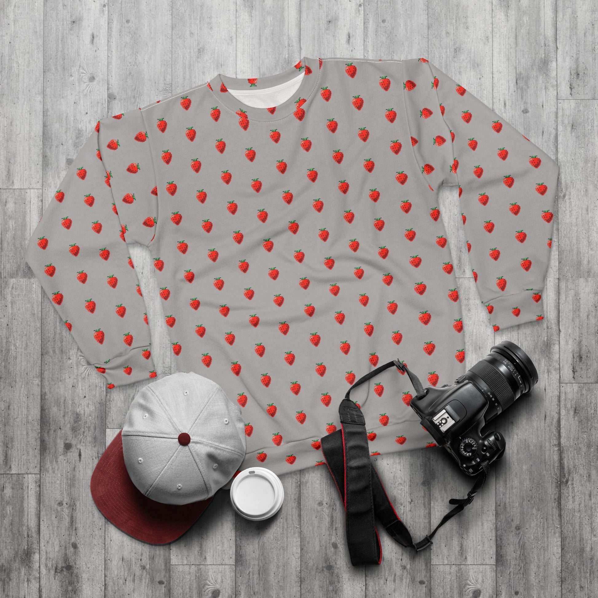 Styled flat lay of 8-bit Strawberry Sweatshirt with cap and camera accessories