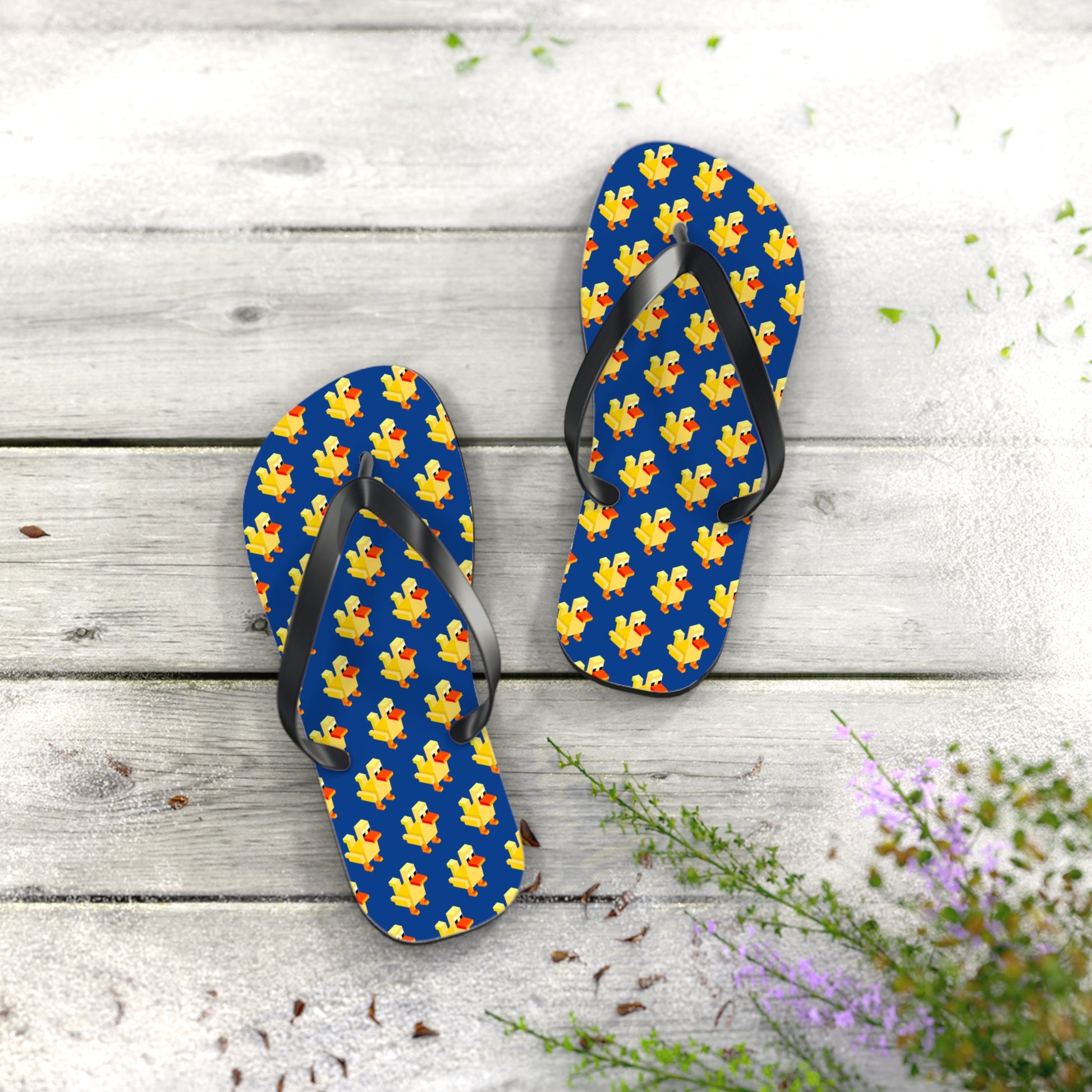 Pair of retro pixel duck flip flops photographed on wooden floor with flowers
