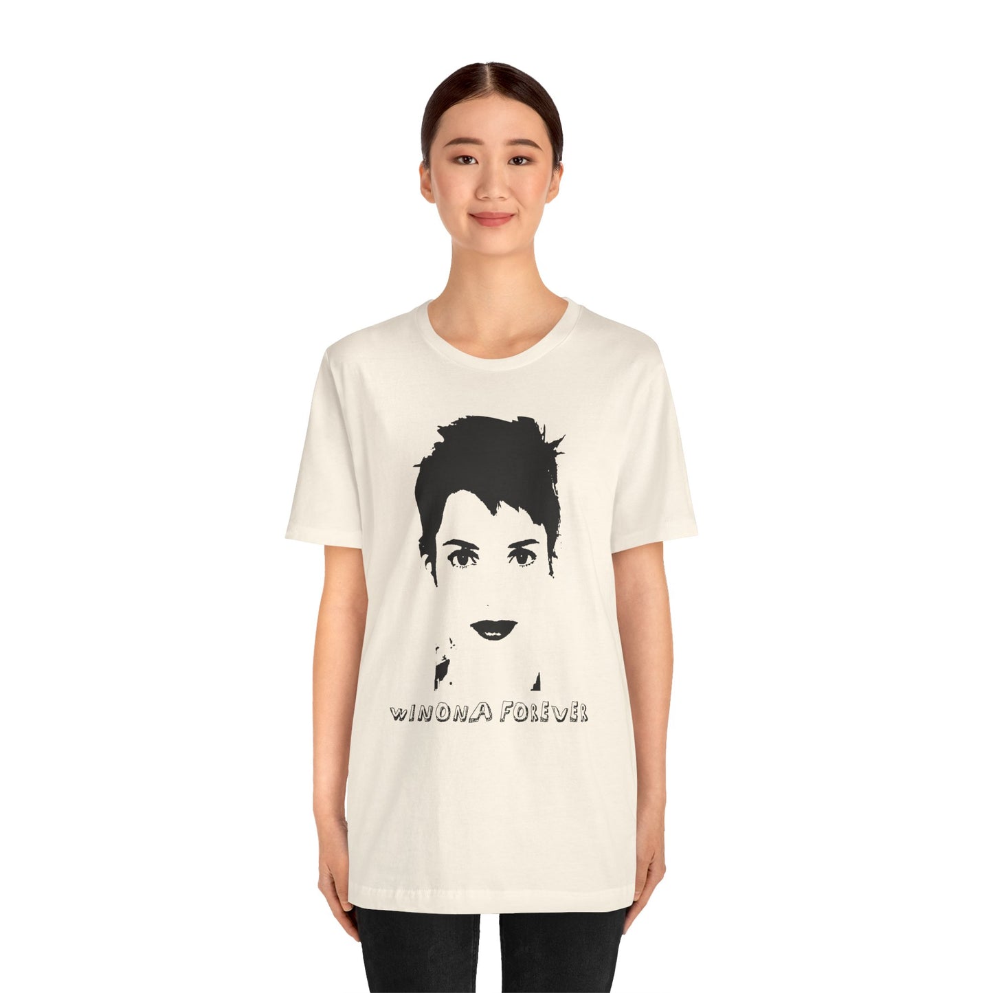 Person wearing a cream Winona Forever T-shirt featuring a minimalist black portrait of Winona Ryder.