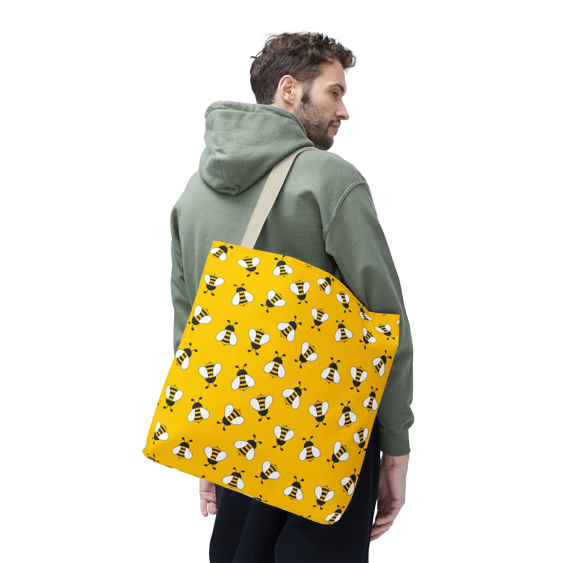 Man carrying a yellow tote bag with bee pattern on a white background