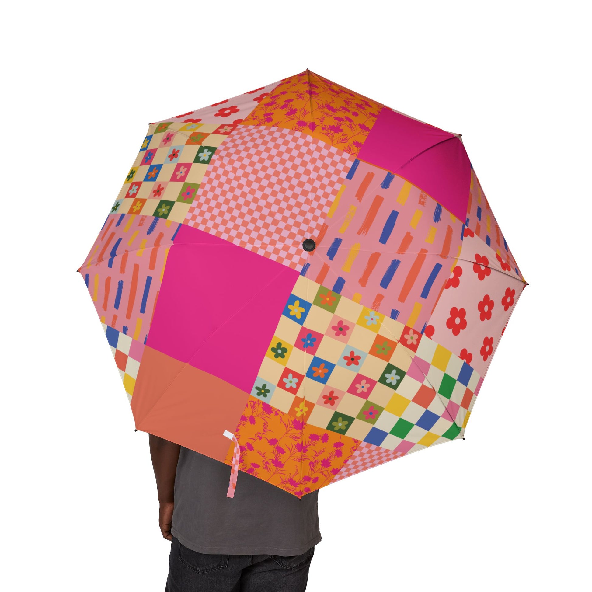 Person holding a pink patchwork-style semi-automatic umbrella with floral and checkered quilt-inspired patterns