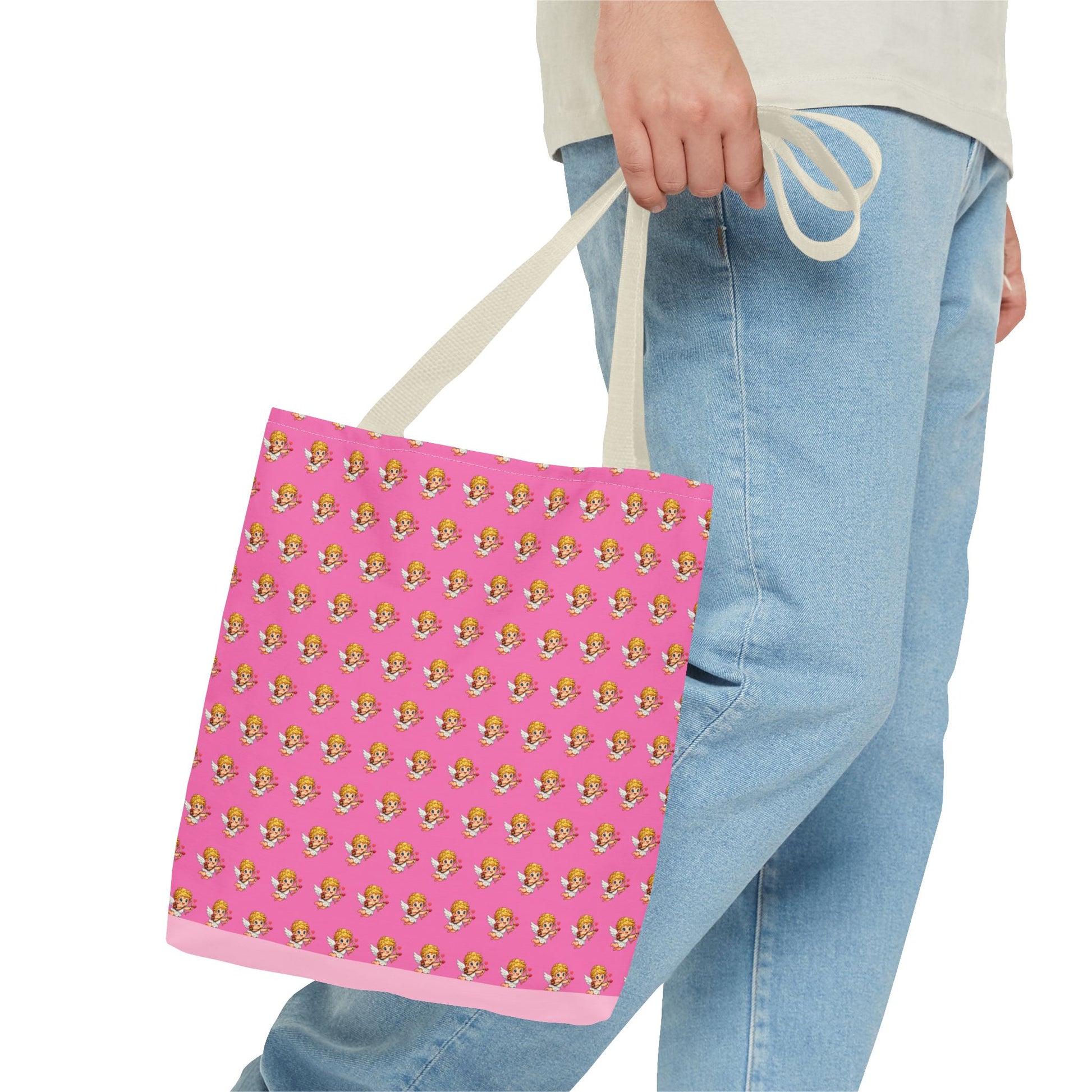 Person holding a pink tote bag with a pattern, wearing light blue jeans and a beige sweater.