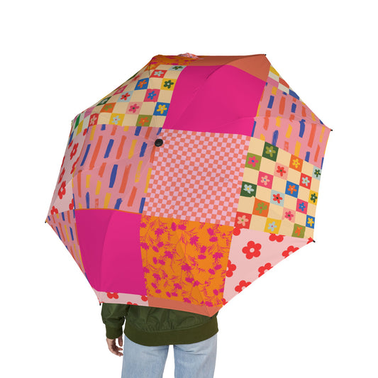 Person holding a pink patchwork-style semi-automatic umbrella with floral and checkered quilt-inspired patterns
