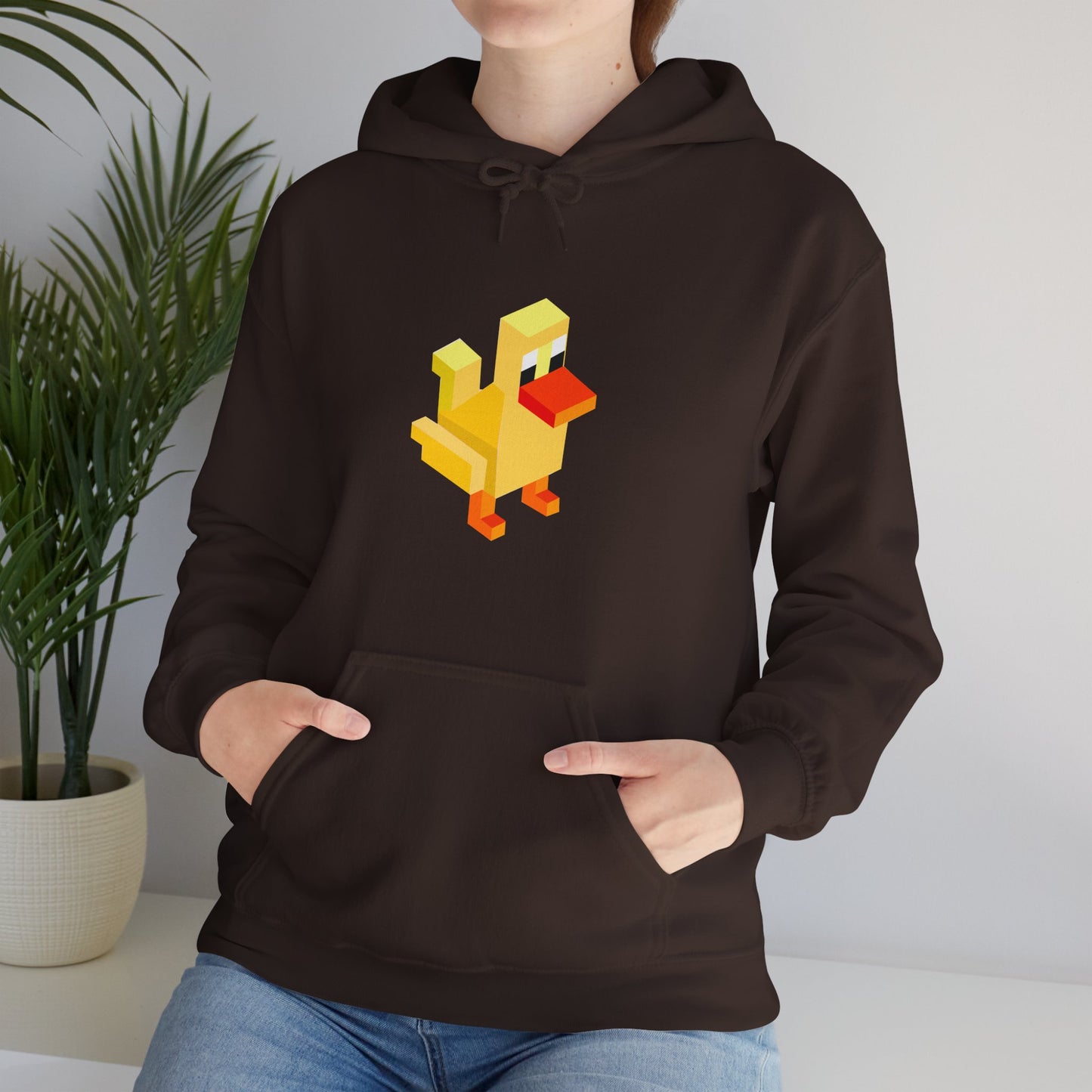 Dark brown pixel duck hoodie worn casually indoors, retro gaming streetwear unisex sweatshirt