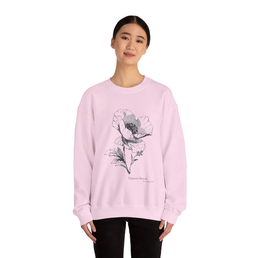 Woman wearing a light pink sweatshirt with a detailed black botanical illustration of a poppy flower and the text "Papaver rhoeas – Eternal peace" on the front.

