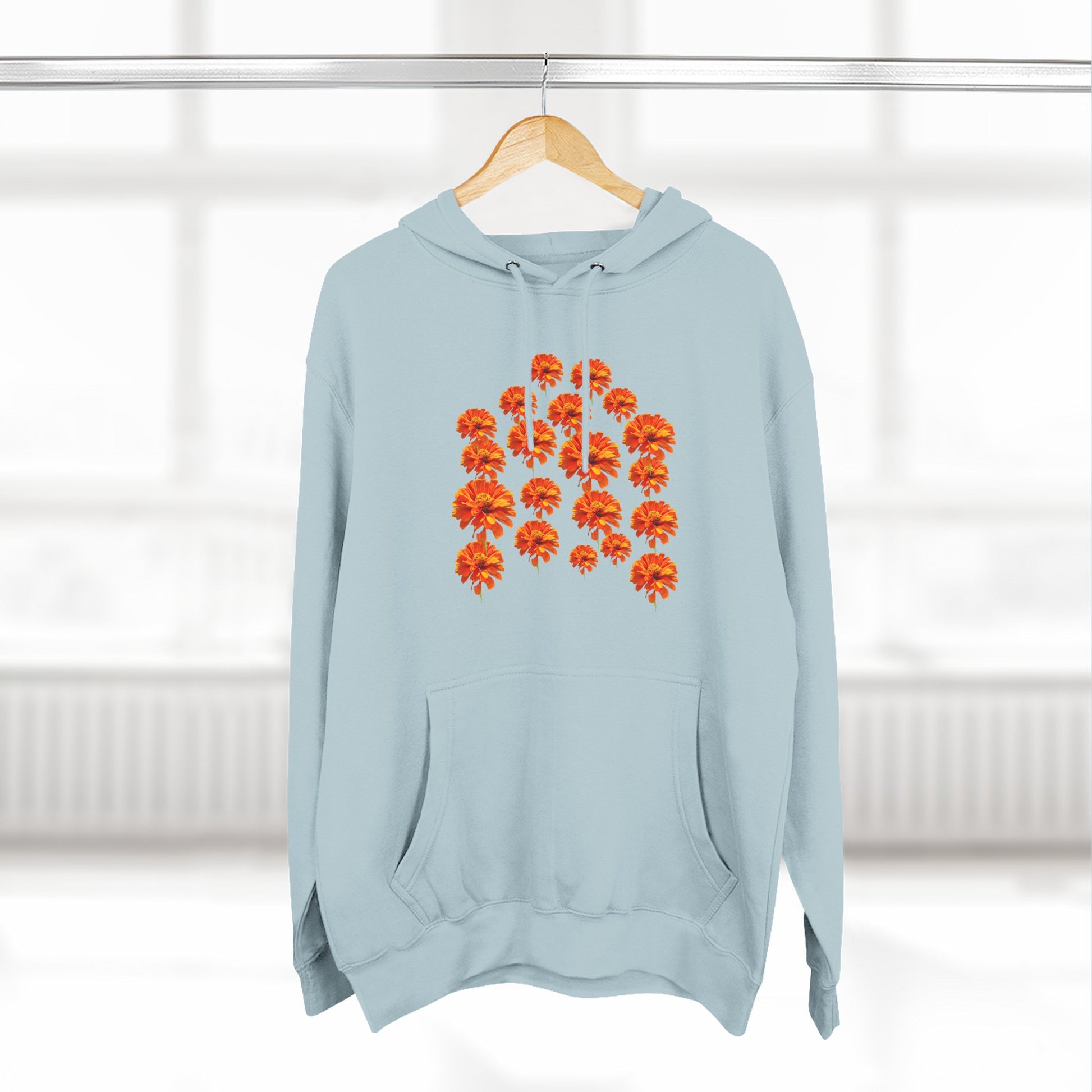 Light blue Zinnia Hoodie on a hanger with orange flower design