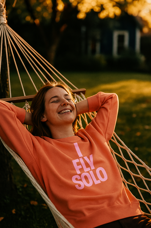 I Fly Solo Unisex Sweatshirt worn by woman relaxing in a hammock at sunset