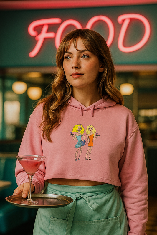 Woman wearing a pink hoodie with cartoon designs, holding a drink in a neon-lit setting.