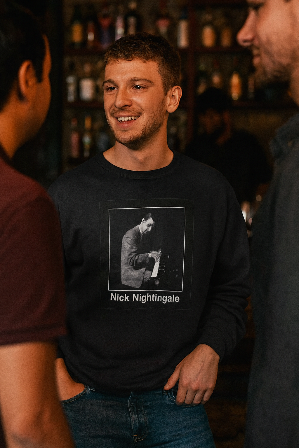 A man wearing the black Nick Nightingale sweatshirt while smiling and talking with friends at a bar.