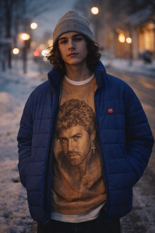 Person wearing George Michael portrait unisex sweatshirt layered under a Blinky Men’s Blue Puffer Jacket on a snowy city street at dusk