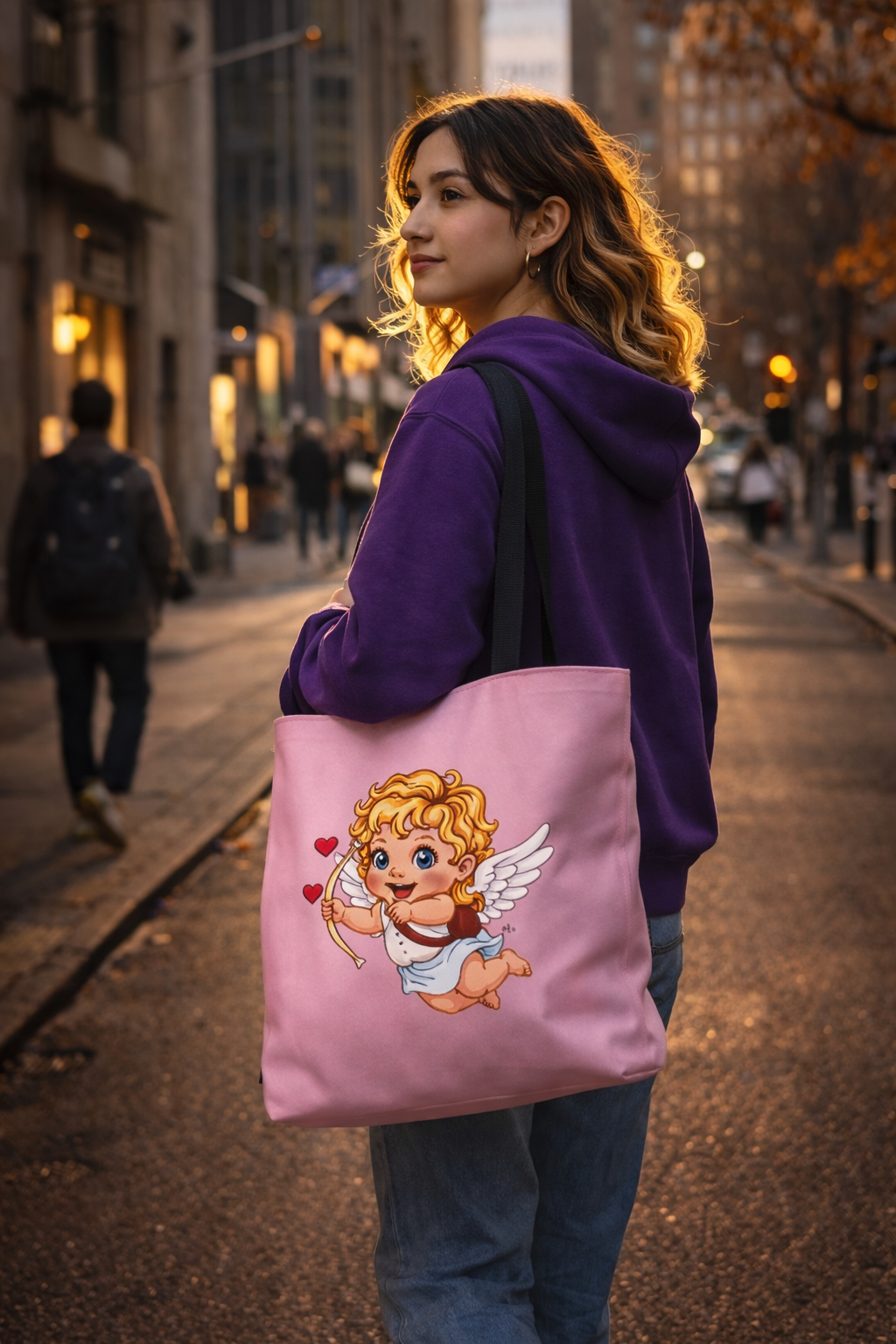 Woman holding a pink tote bag with a cupid design on a city street.