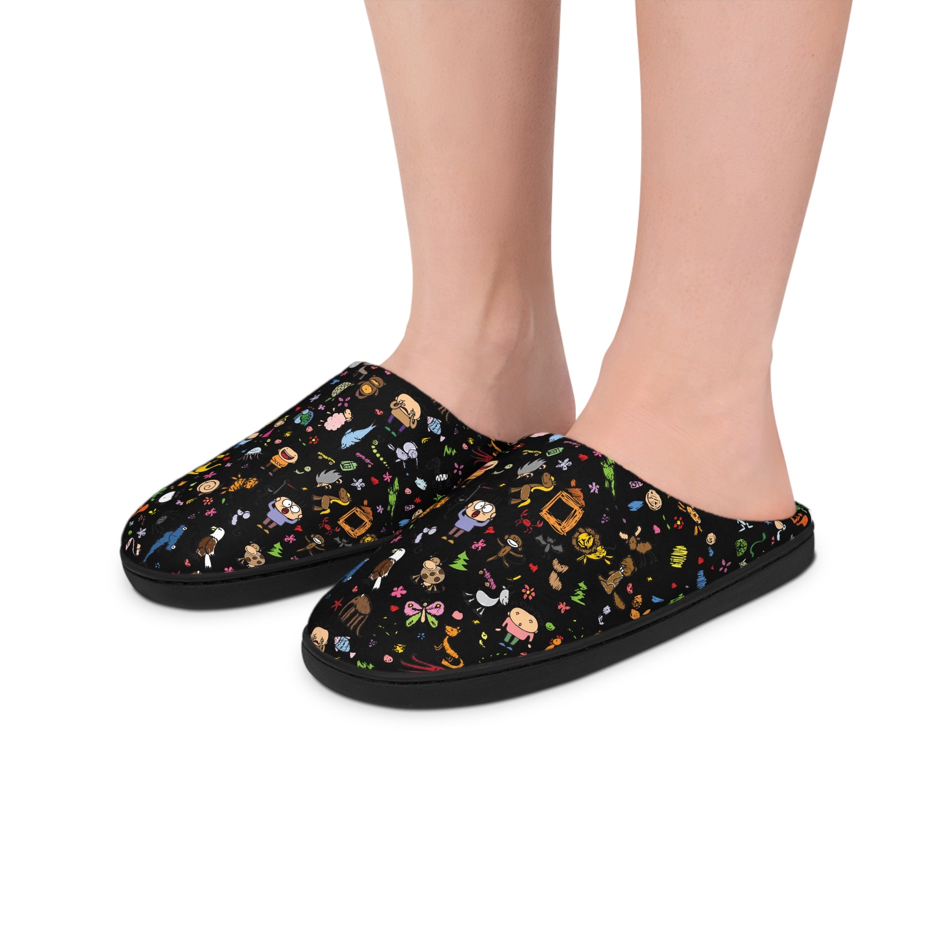 Close-up of Women’s Cartoon Cozy Slippers on feet, showing the colorful cartoon-style design on a black background with soft white fleece lining.