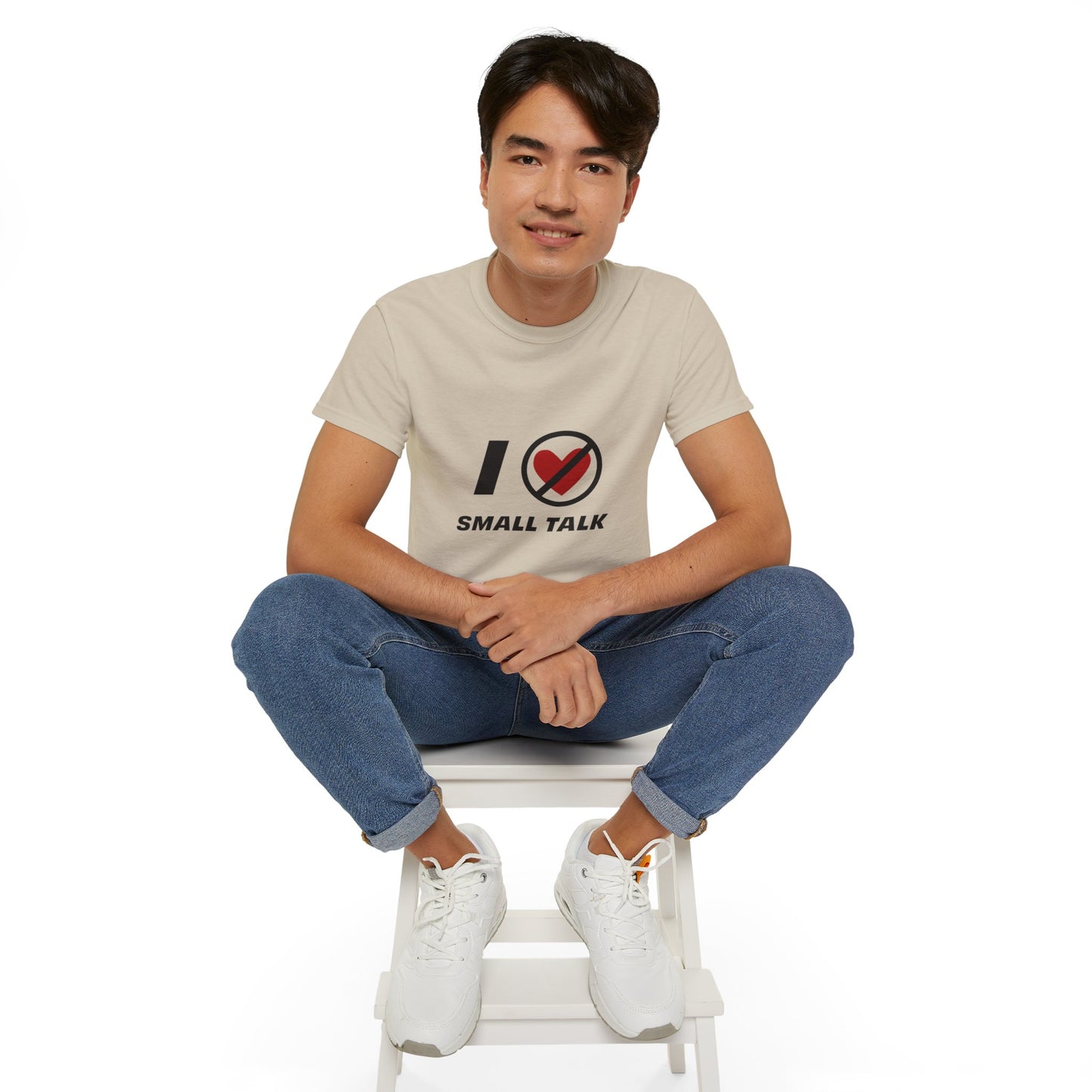 Man wearing beige unisex I Hate Small Talk T Shirt sitting casually