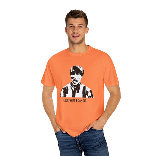 Man modeling orange Stuart MadTV T-shirt with bold graphic and “Look what I can do!” quote.