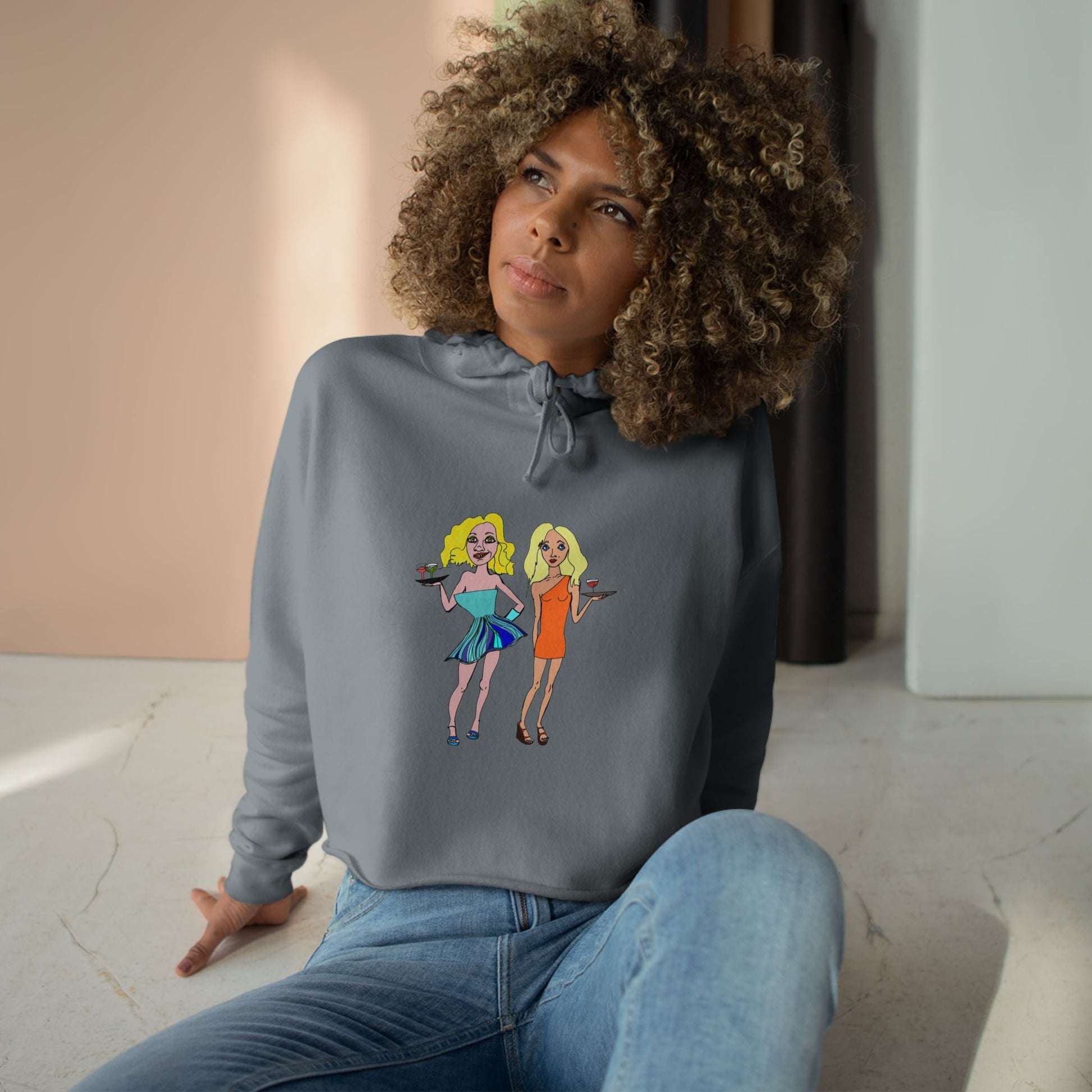 Model wearing the gray Waitress Crop Unisex Hoodie with original waitress artwork in a seated pose