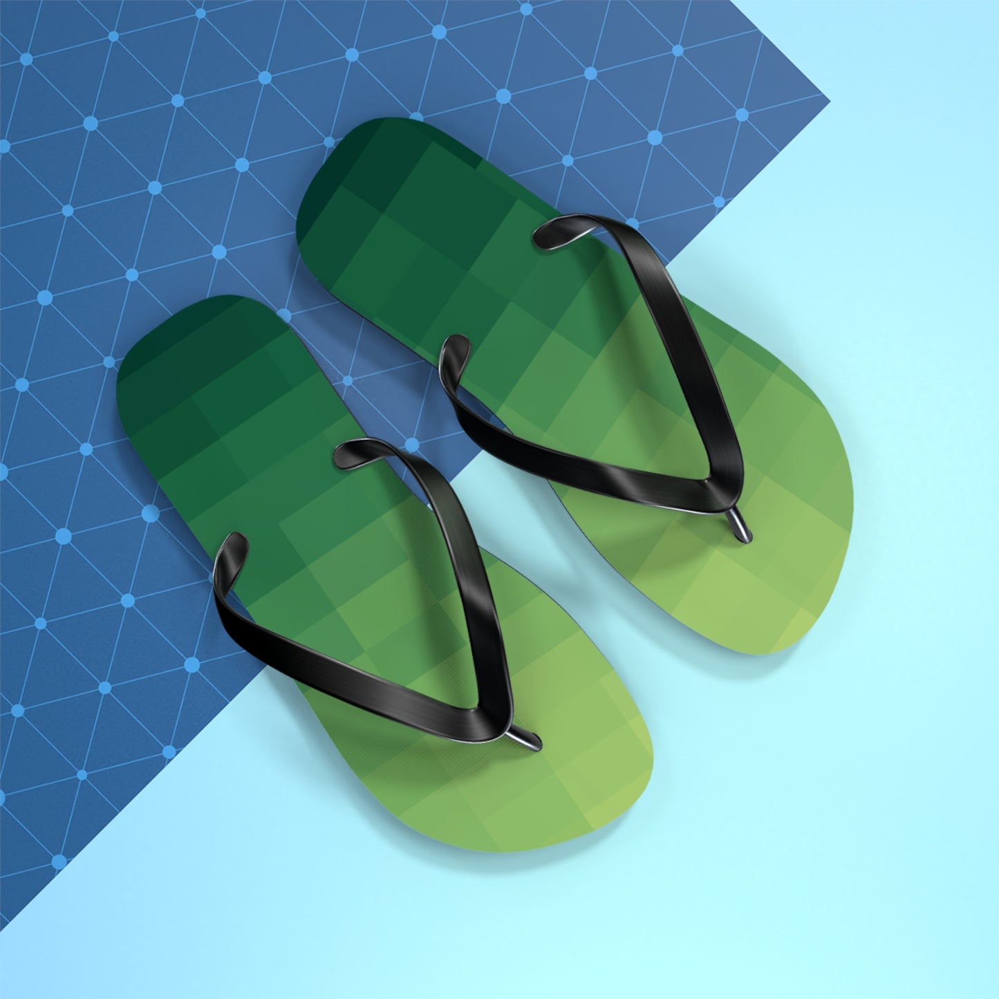 Green pixel-art inspired flip flops with black straps photographed on a bright geometric blue background