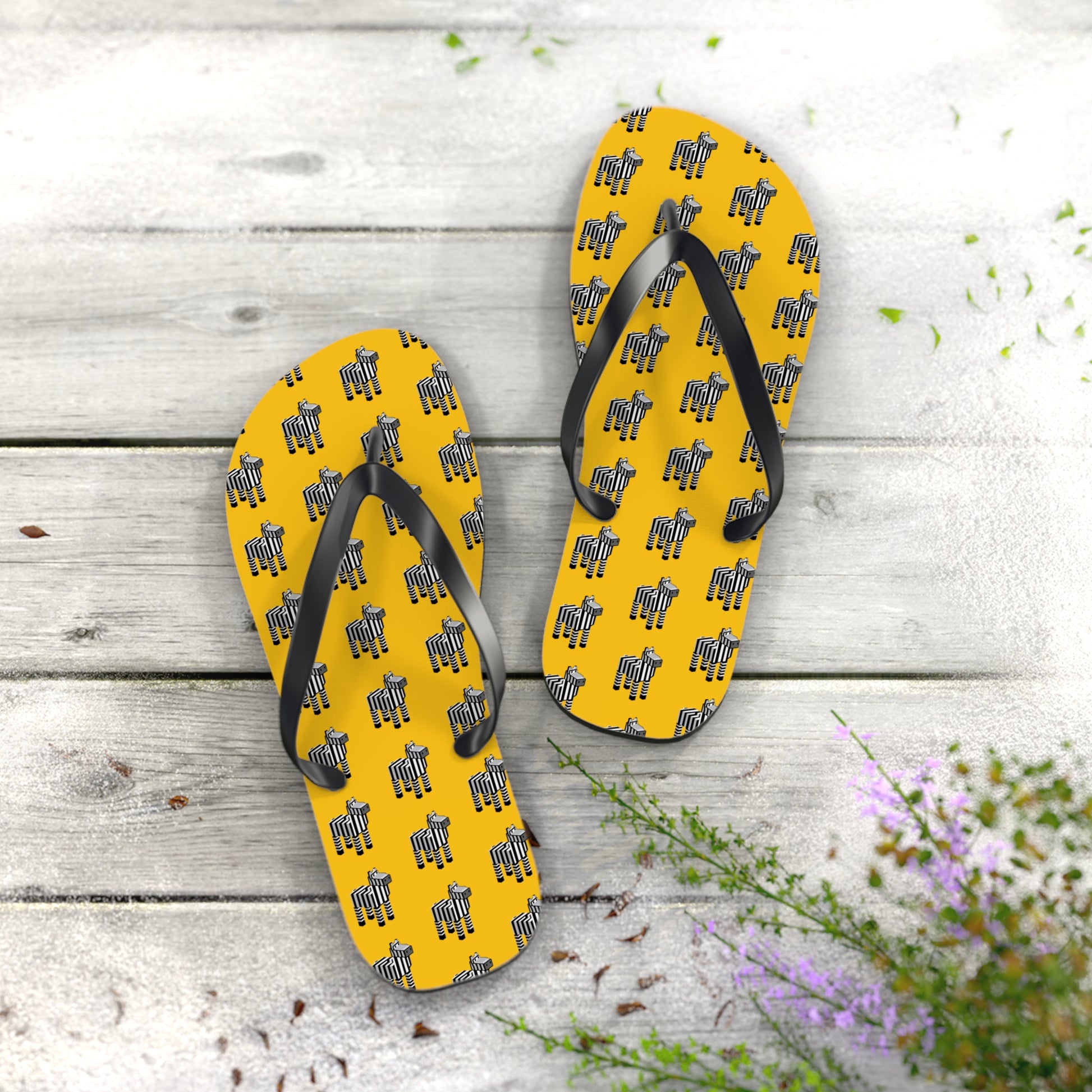 Pair of Arcade Zebra Flip Flops with yellow base and zebra pattern placed on wooden surface.