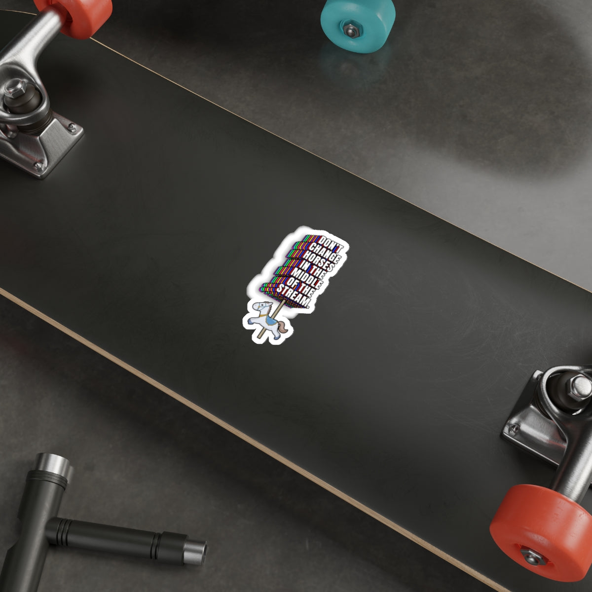 Don’t Change Horses in the Middle of the Stream sticker placed on a black skateboard deck