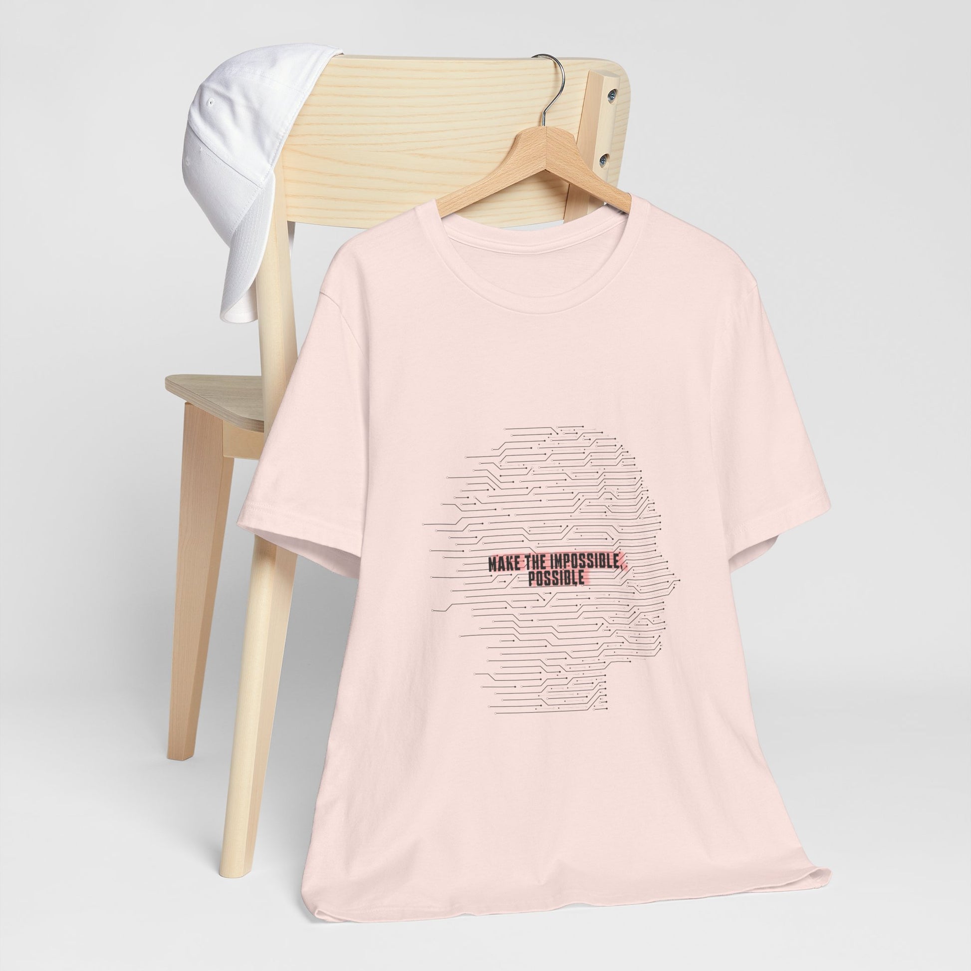Pink Make It Possible T-Shirt on chair with futuristic message design.