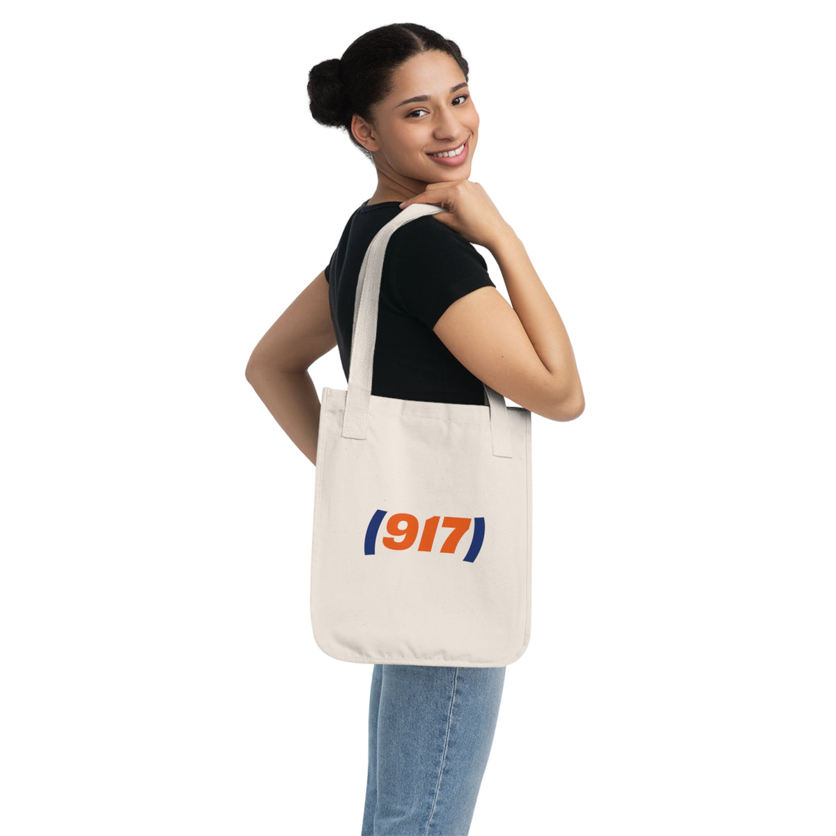 Woman carrying a natural canvas 917 NYC tote bag with orange and navy graphic print.