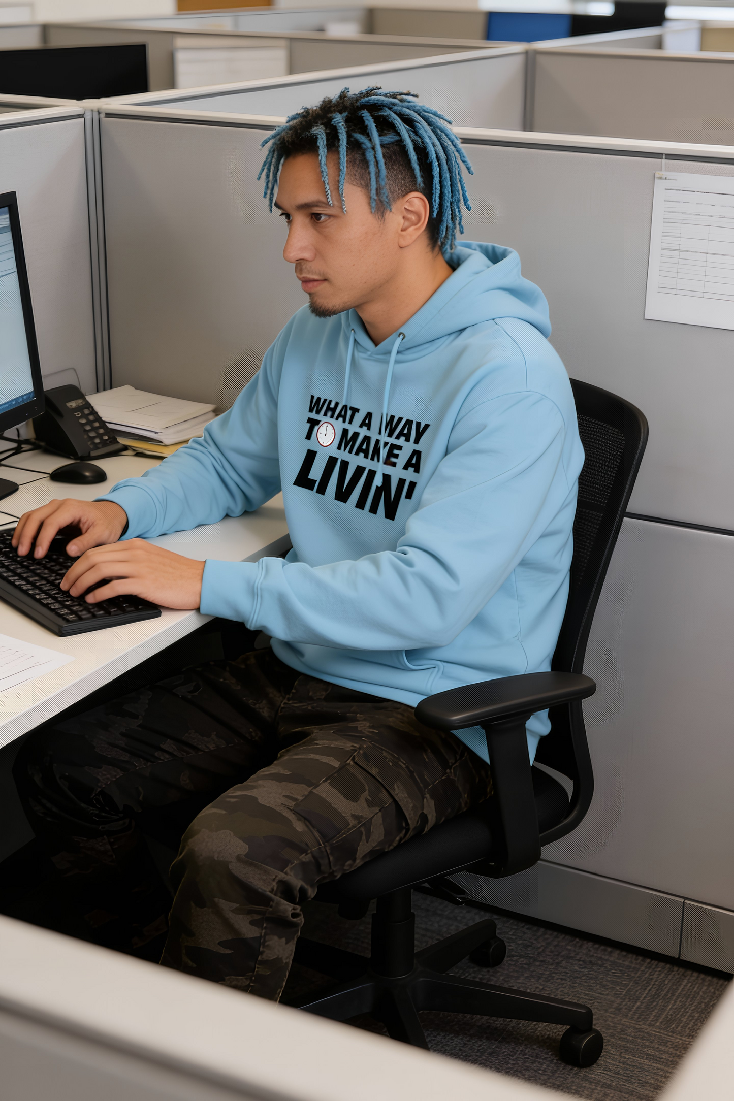 Model sitting in office cubicle wearing light blue 9 to 5 hoodie