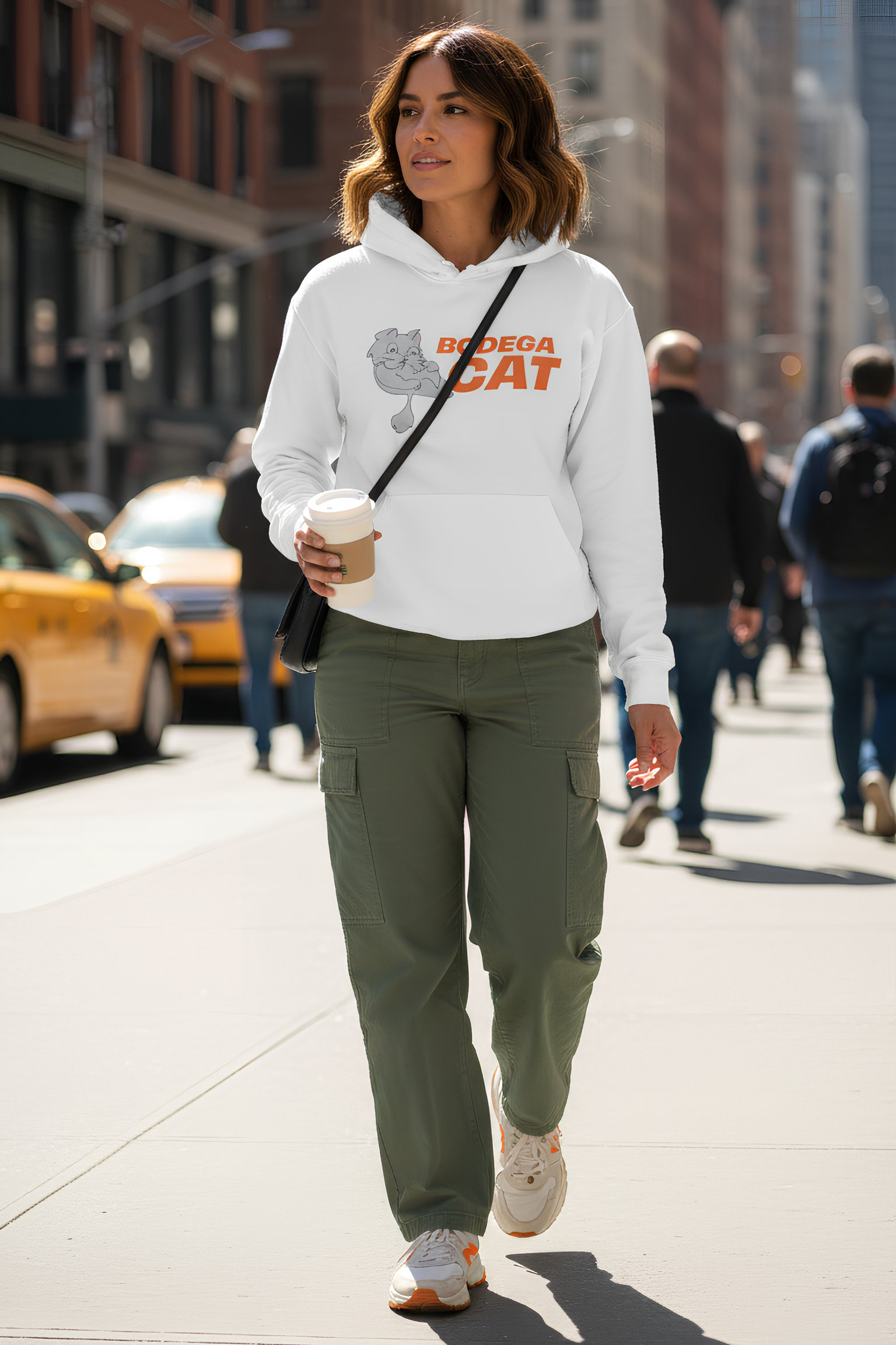 Woman walking in city wearing white Bodega Cat hoodie