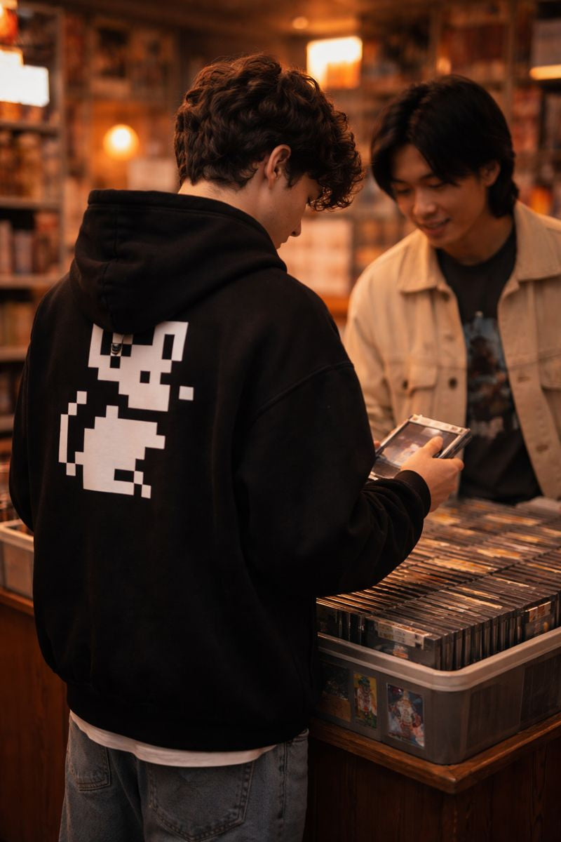 Person wearing black zip hoodie with white pixel mouse graphic on the back in a record store