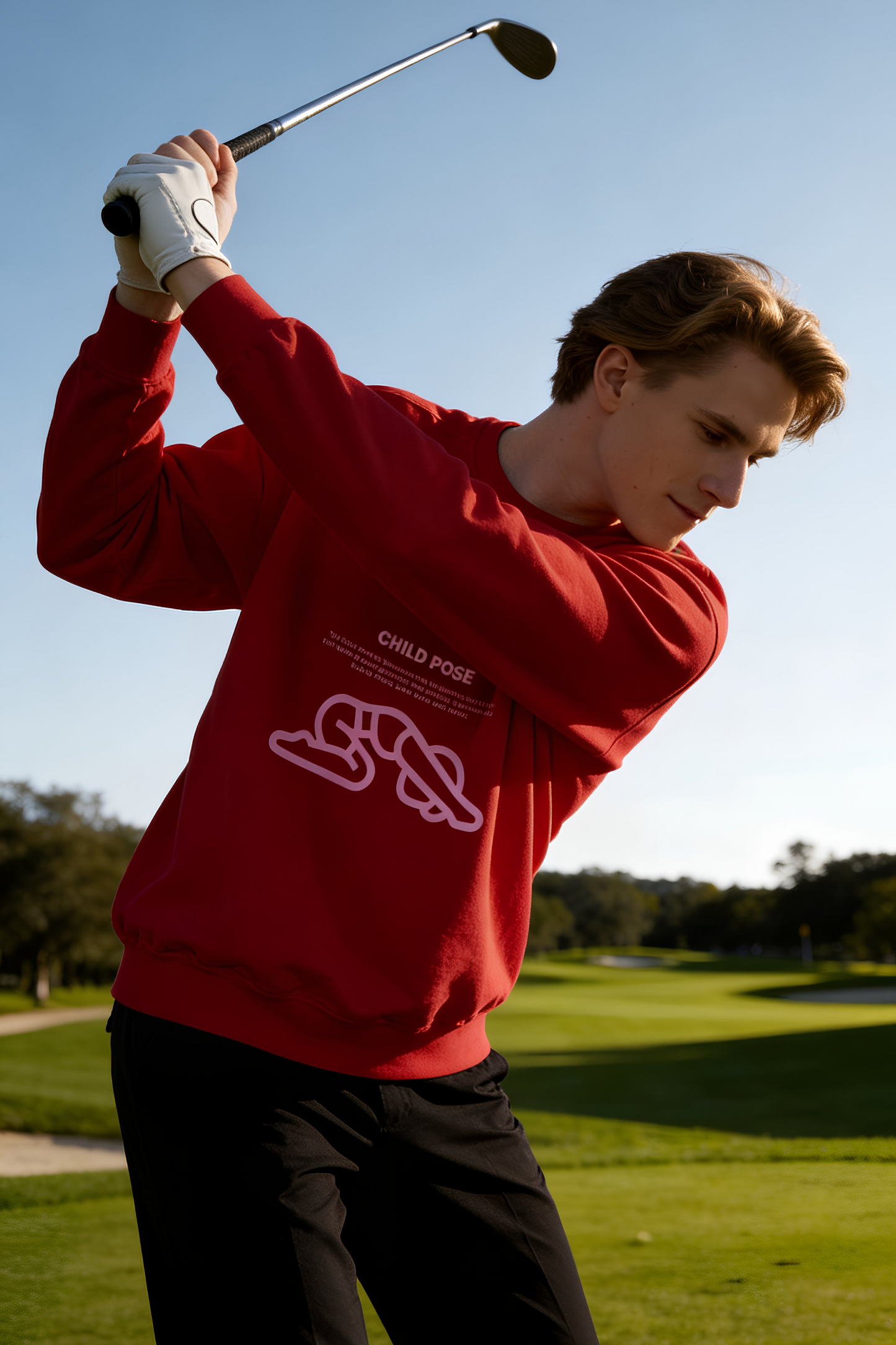 Man golfing wearing red Child Pose sweatshirt outdoors