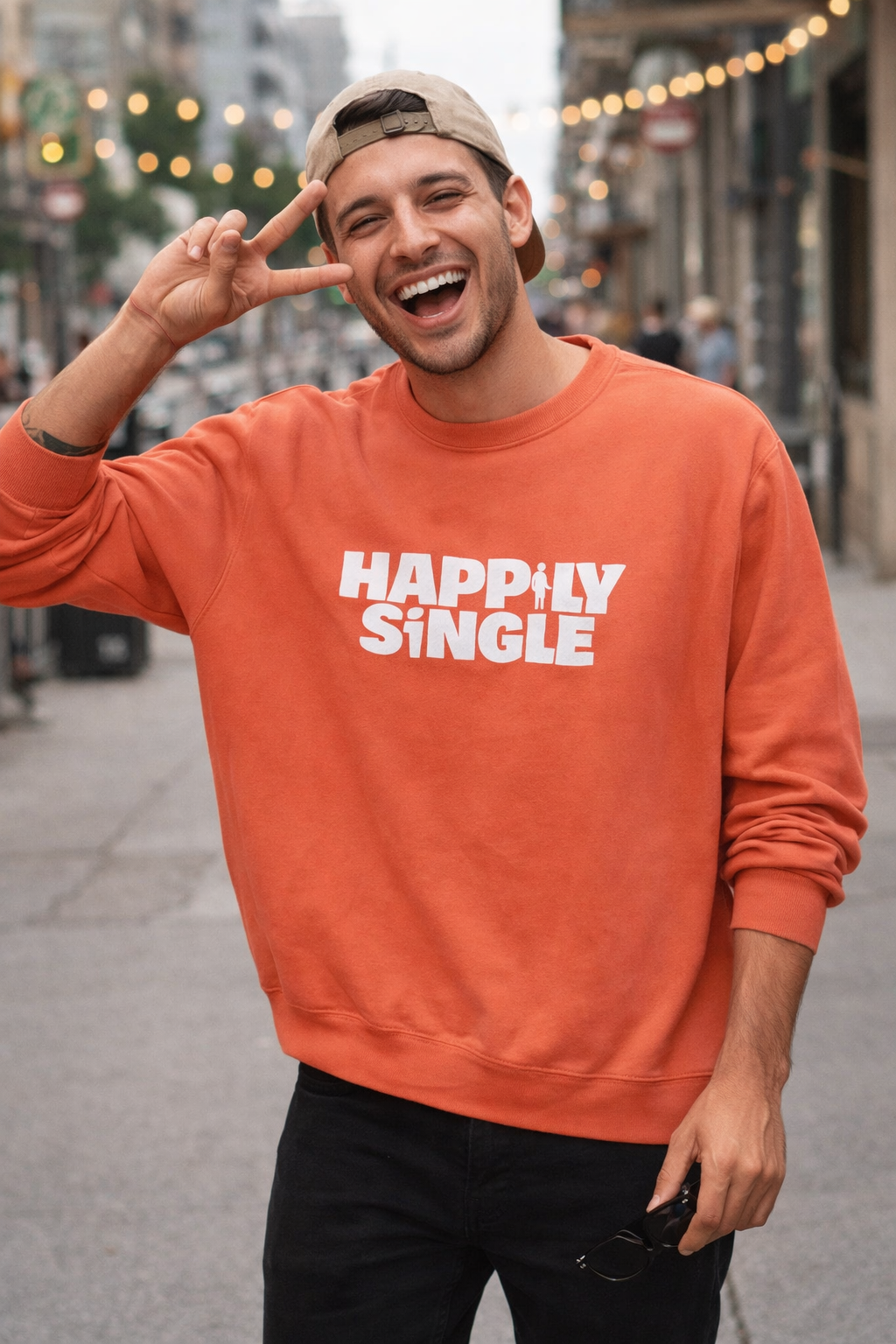Smiling man wearing terracotta “Happily Single” sweatshirt on city street
