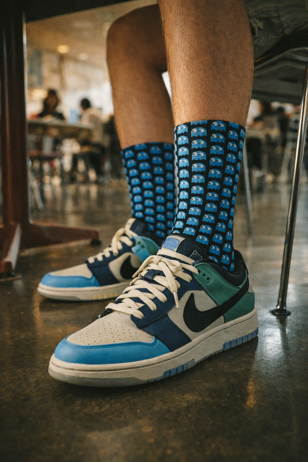Inky Ghost Crew Socks – Retro Arcade Gamer Socks worn with blue and white sneakers in a cafe or indoor public space