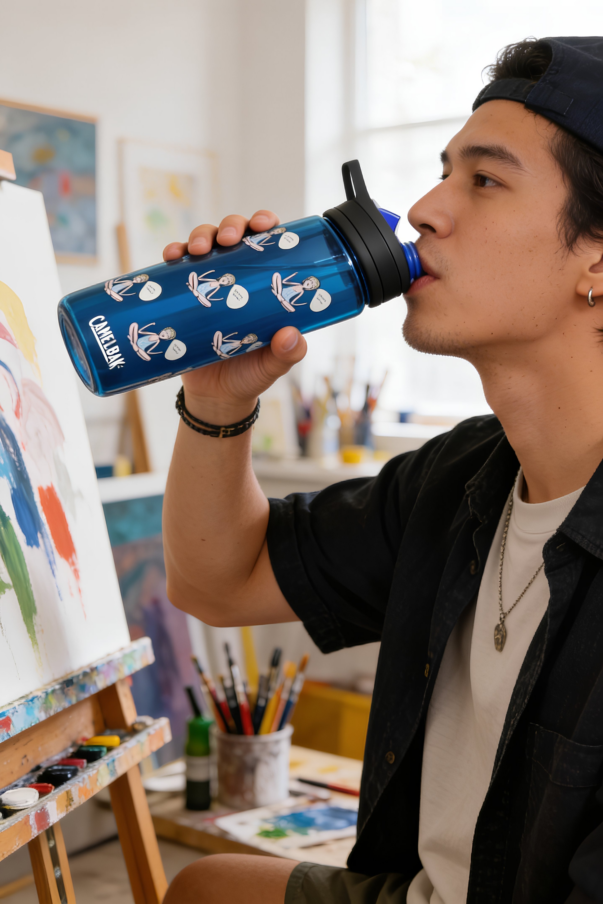 Person drinking from navy blue Log Out reusable water bottle indoors