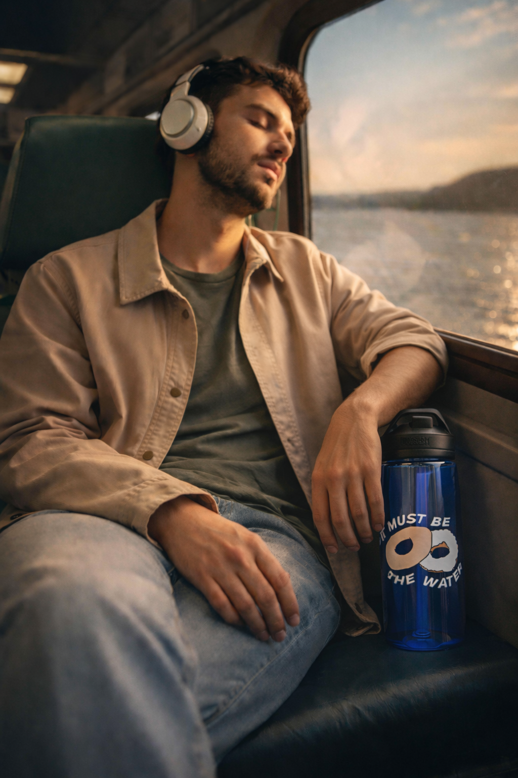 It Must Be The Water 25oz reusable bottle with donut bagel design held by commuter on New York train