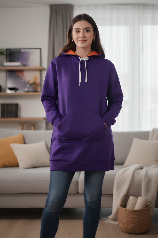 Woman wearing purple hoodie dress with orange hood lining standing indoors, casual cozy outfit