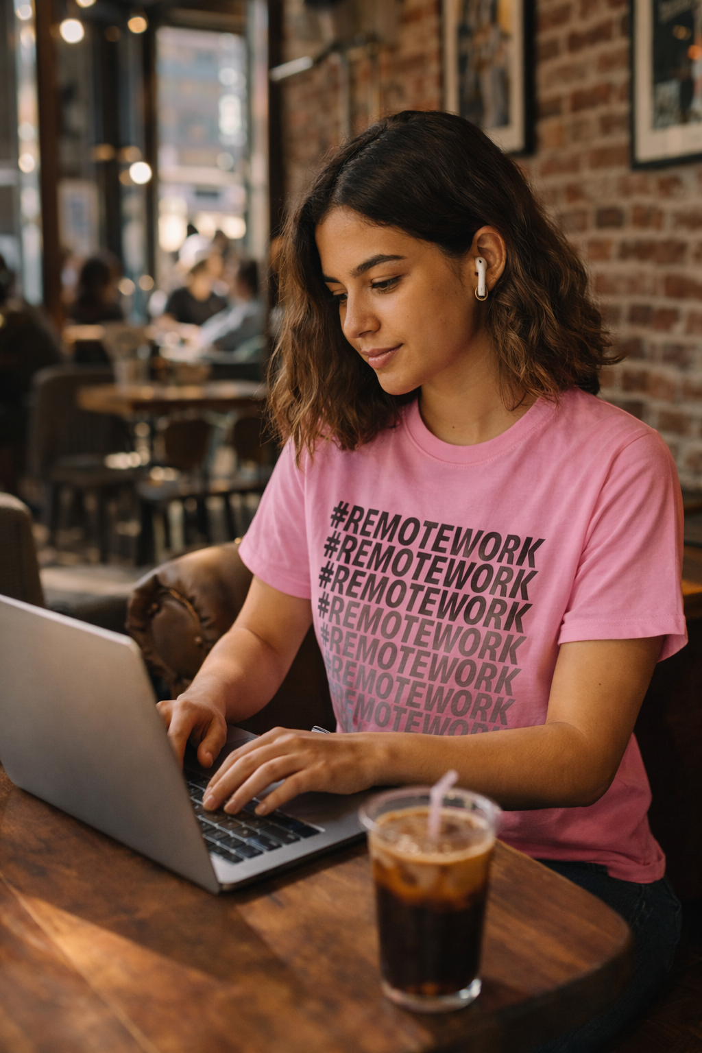 woman wearing pink remote work t shirt working at cafe laptop