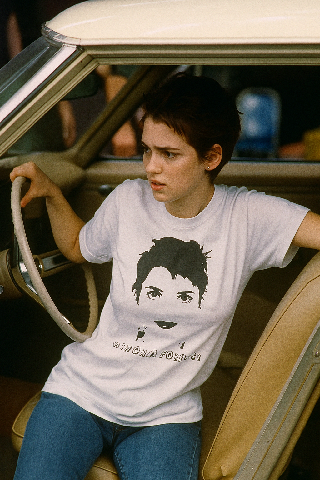 Person sitting in a vintage car wearing a white T shirt with a graphic face print.