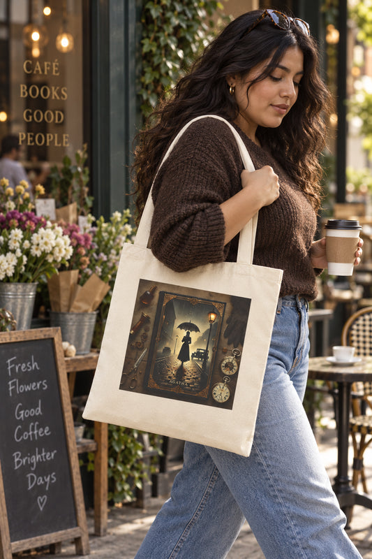Woman carrying Agatha mystery book tote bag in natural canvas outside a cafe