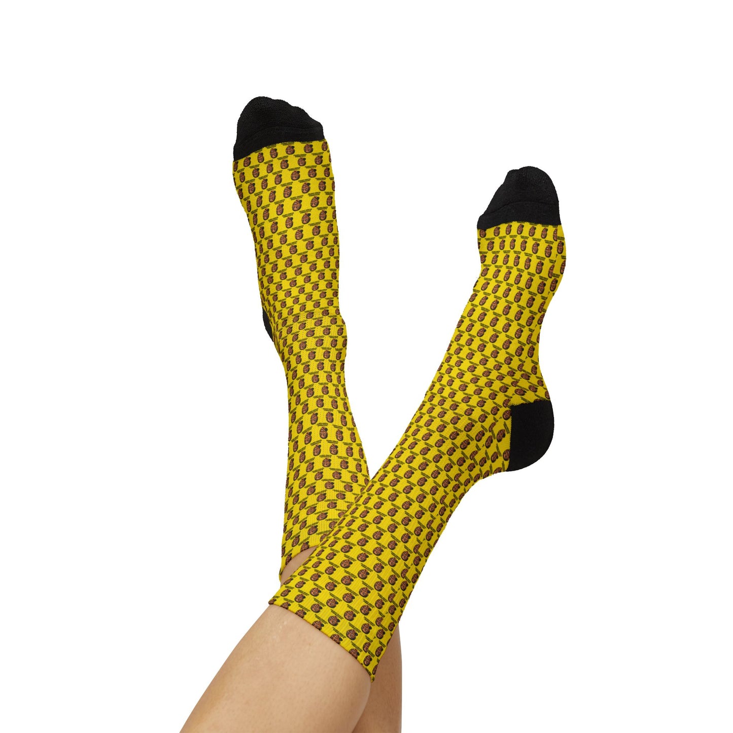 Person relaxing with legs raised while wearing yellow AOC crew socks featuring repeating Alexandria Ocasio-Cortez artwork.
