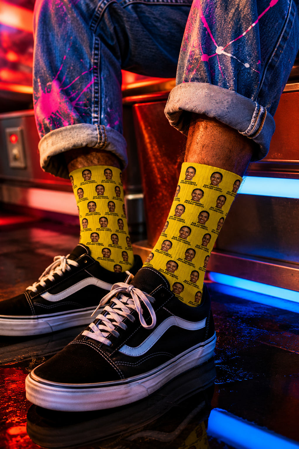 Male Gen Z wearing yellow AOC crew socks with repeating Alexandria Ocasio-Cortez artwork, paired with black Vans sneakers and paint-splattered jeans in a colorful neon arcade setting.