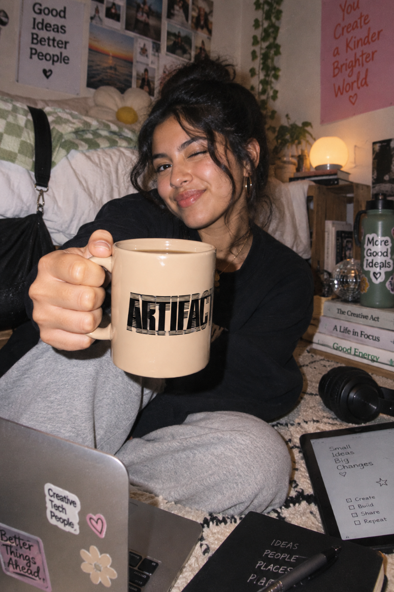 Gen Z student holding beige Artifact Tech Mug in a creative college workspace