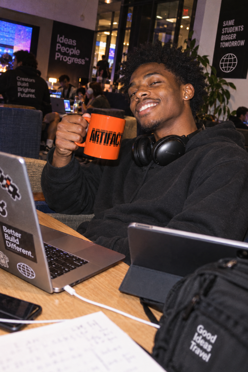 Gen Z student holding orange Artifact Tech Mug in a college tech lounge