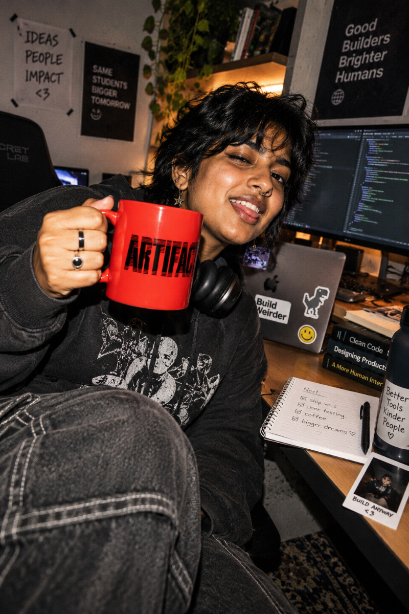 Gen Z student holding red Artifact Tech Mug in a college tech workspace
