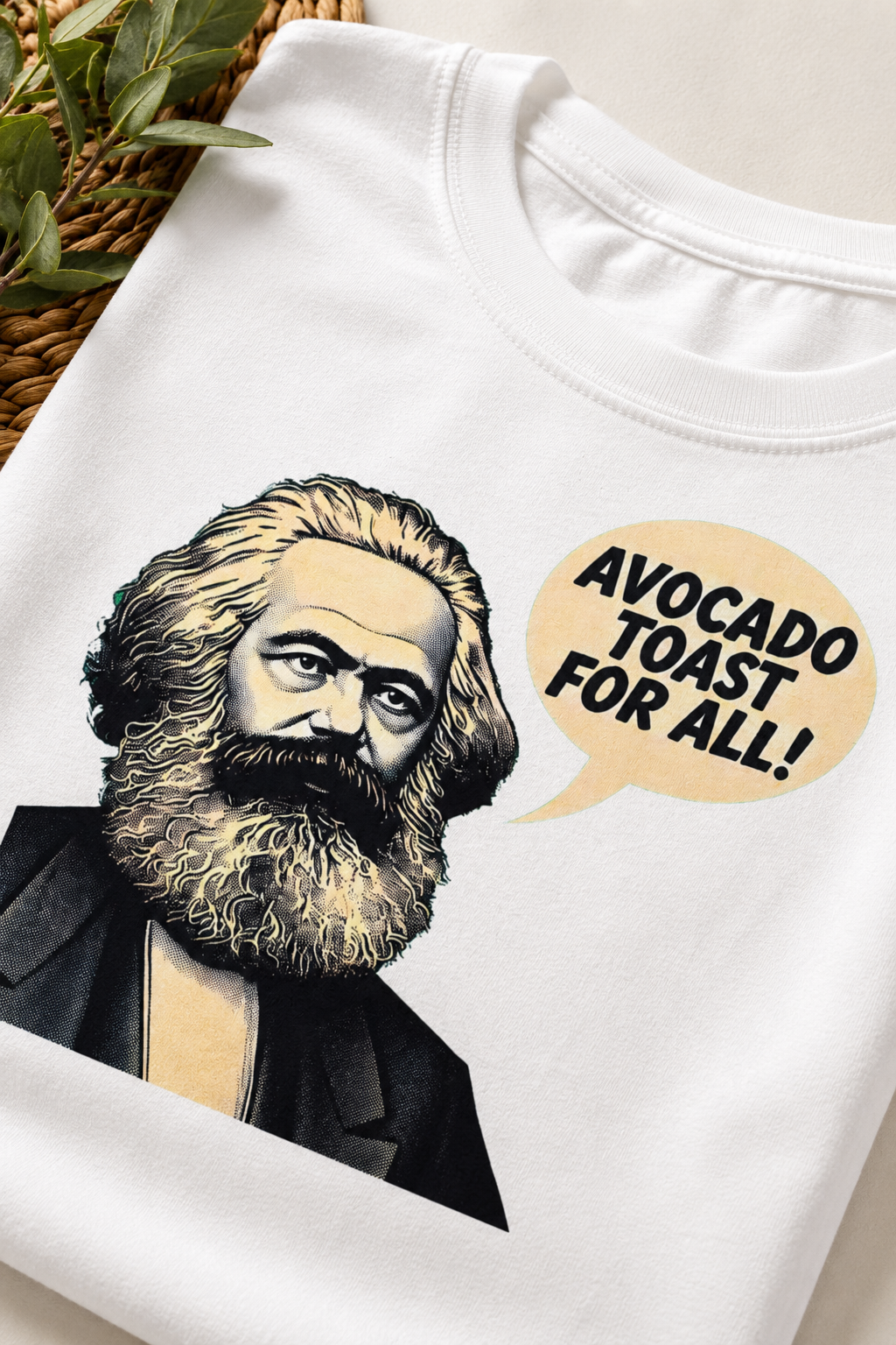 Close-up detail of white graphic t-shirt showing Karl Marx illustration and “Avocado Toast for All” slogan, highlighting print quality and fabric texture.