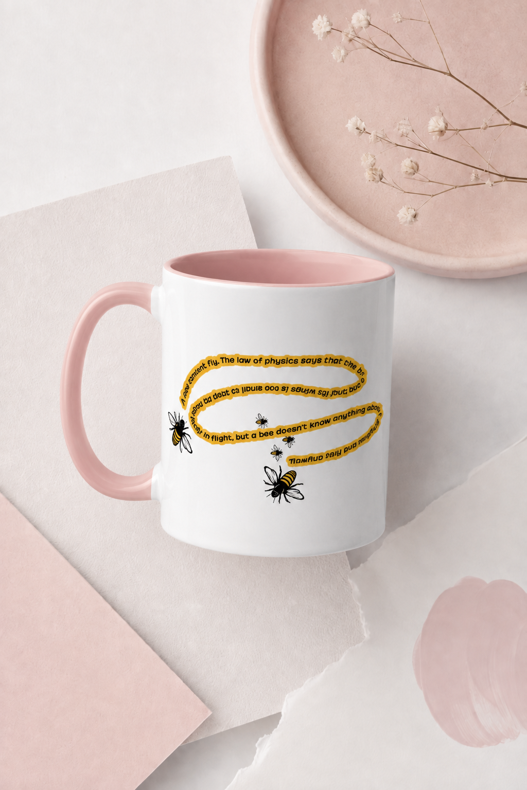 Pink accent bee physics quote mug in a minimal pastel flat lay