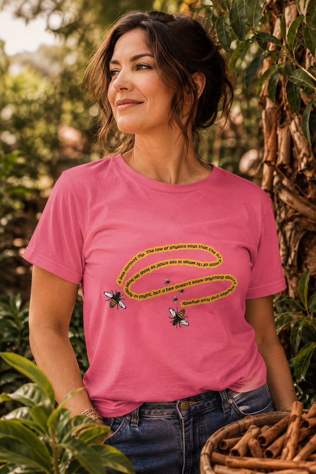 Woman wearing pink bee physics quote T-shirt in a cinnamon farm garden
