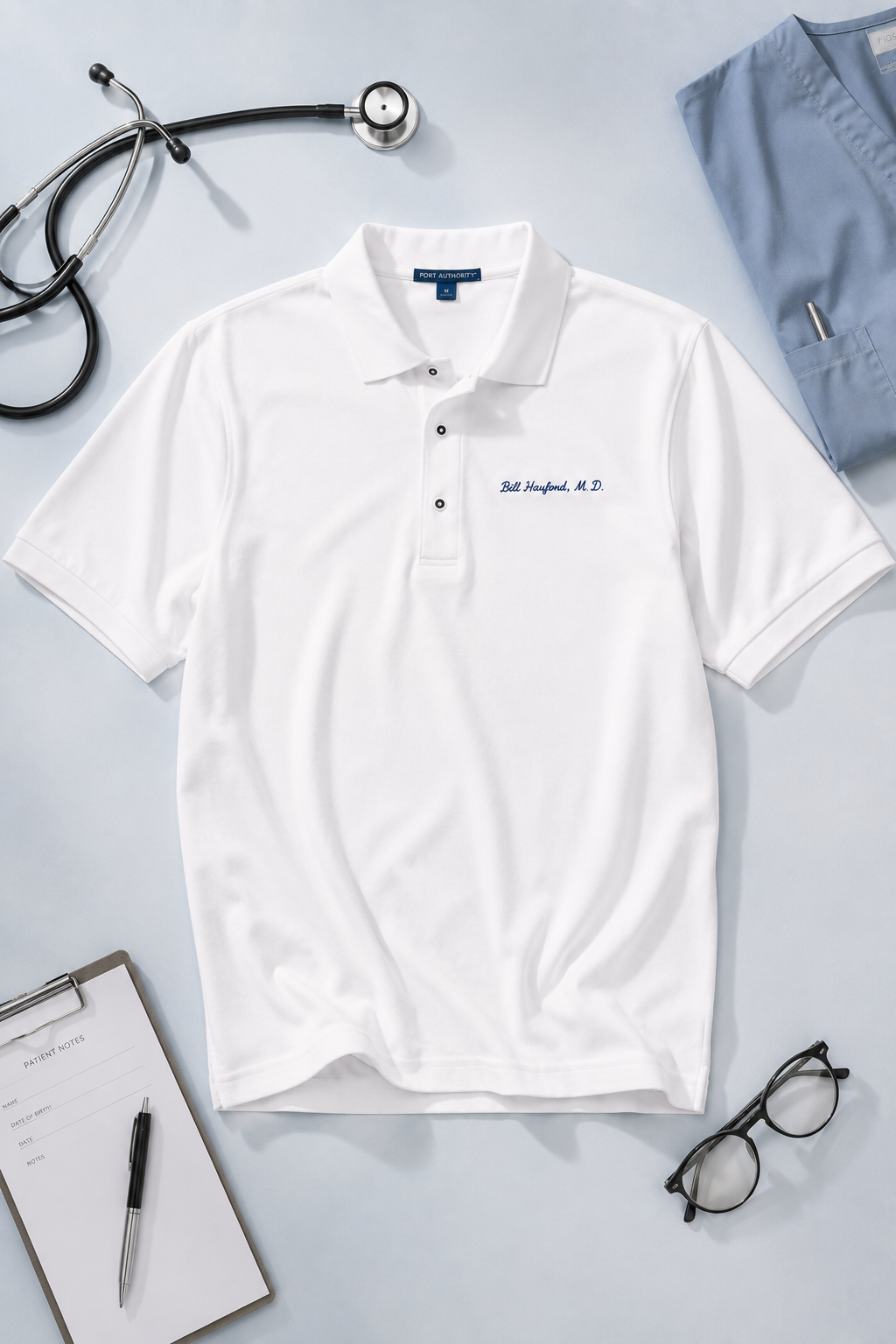 White embroidered doctor polo shirt featuring Bill Hayford M.D. displayed with stethoscope, scrubs, patient notes, and eyeglasses