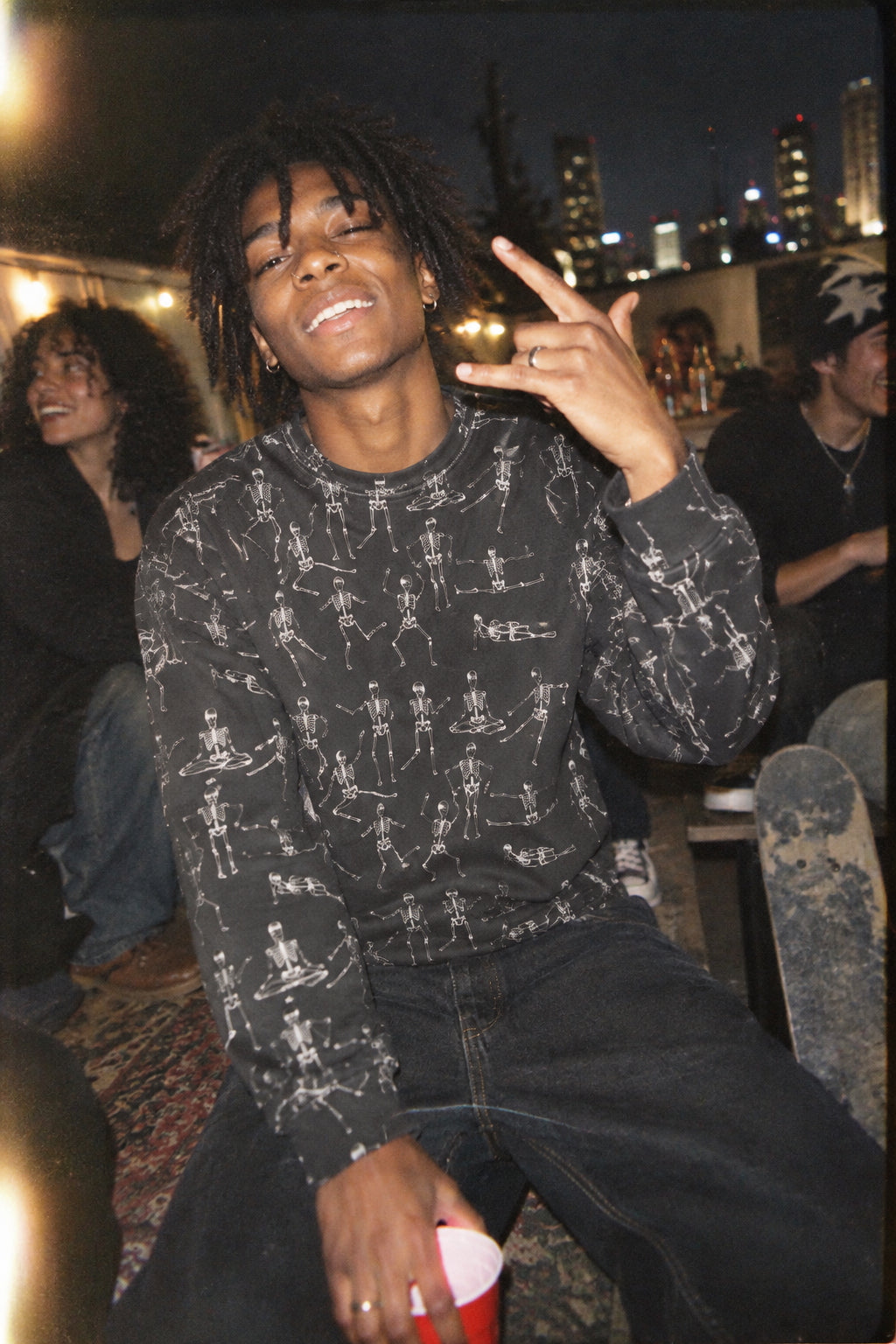 Young man wearing the Black Dancing Skeletons Sweatshirt at a nighttime party