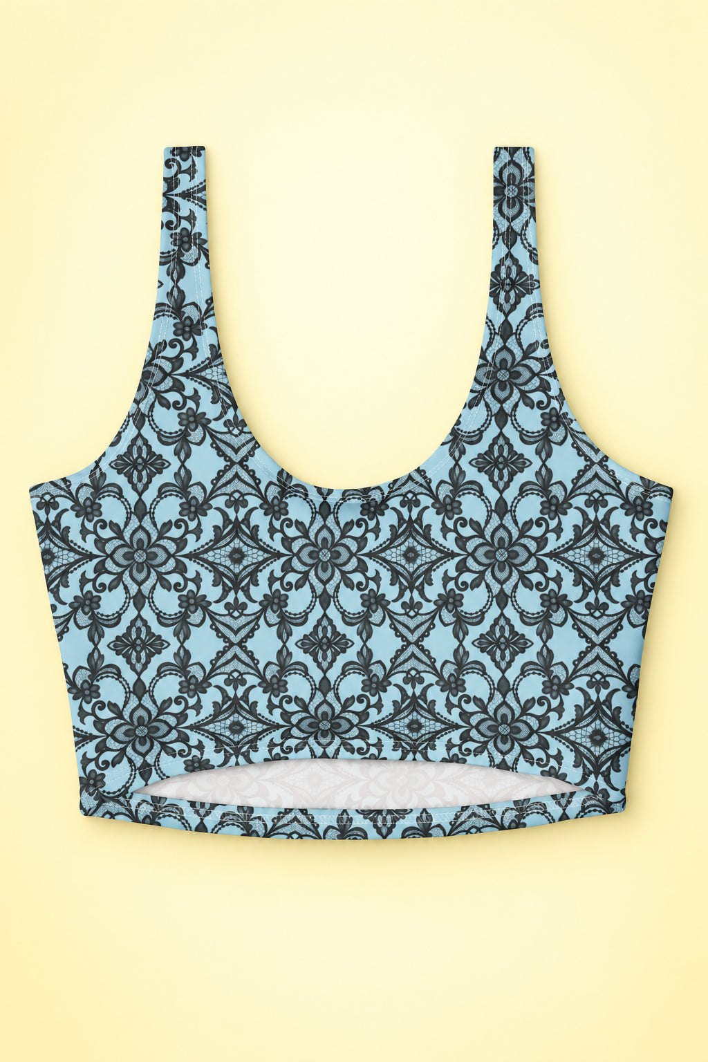 Back flat lay of blue floral lace print sports bra showing the wide straps, U-shaped neckline and lower back cutout on a pastel yellow background.