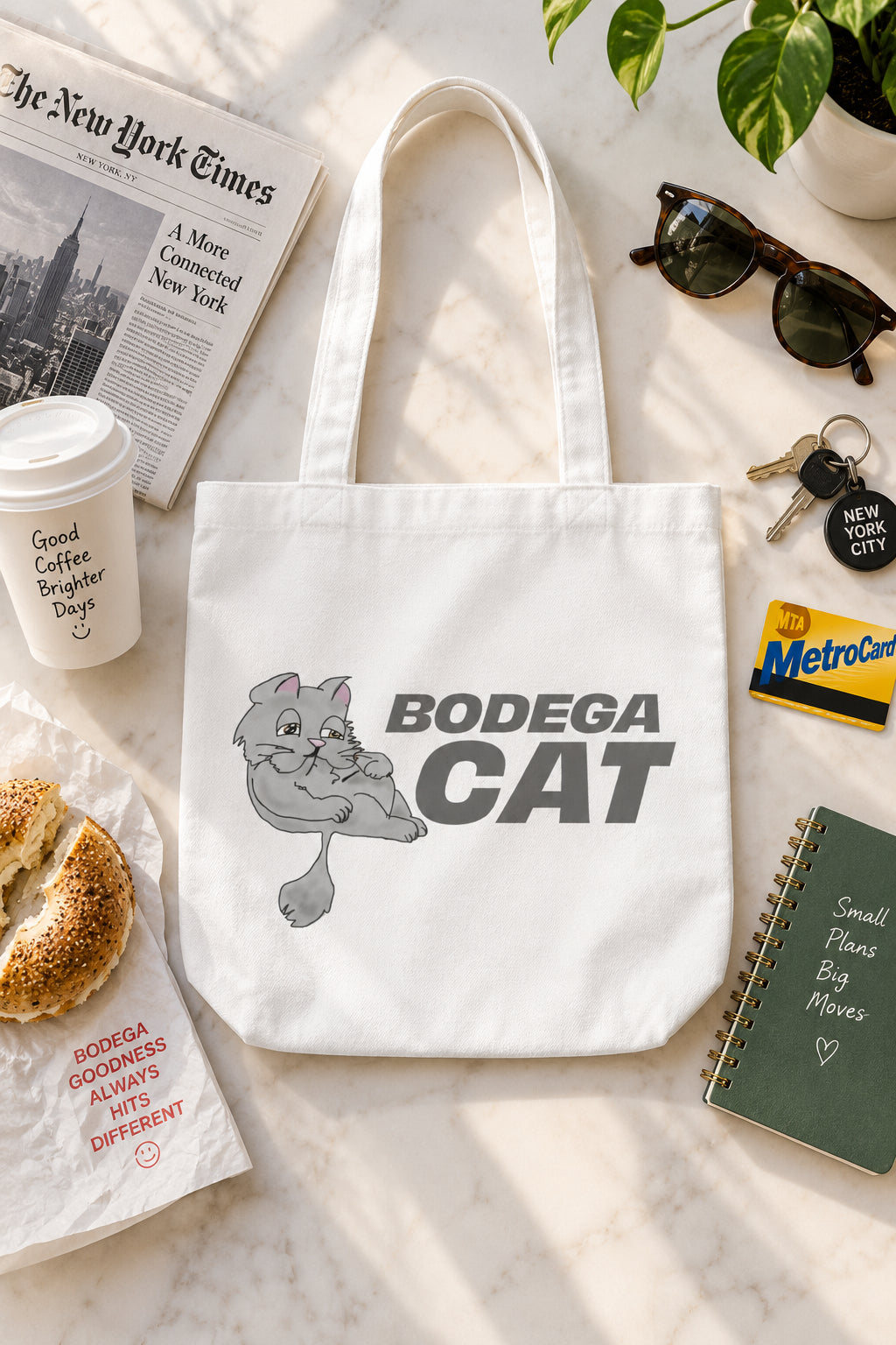 Bodega Cat white 16 x 16 tote bag flat lay with New York City accessories