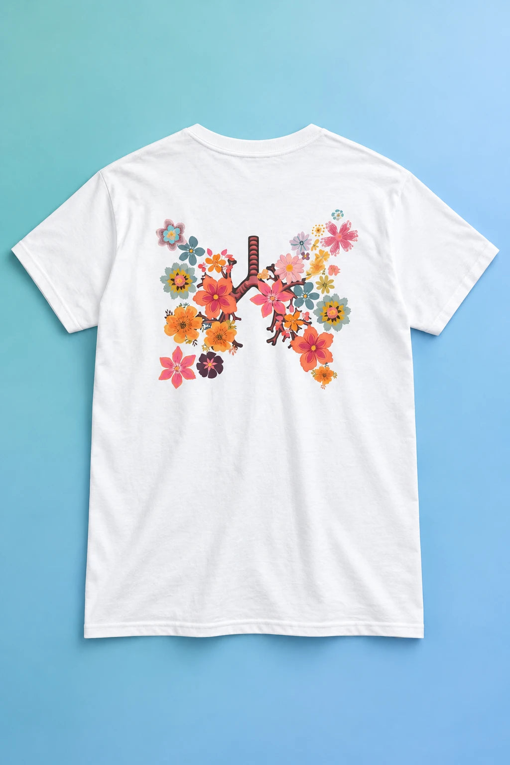 White Breath T-shirt laid back-side up on a blue gradient, showing the colorful floral lungs graphic.
